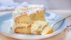 a slice of cake with white frosting and sprinkles on a plate