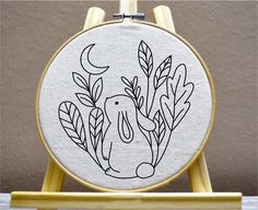 an embroidery hoop with a black and white drawing of a dog in the woods on it