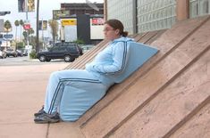 a woman sitting on the side of a wooden wall next to a parking lot with her feet up