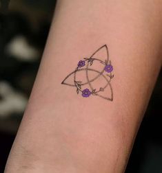 a small tattoo on the arm of a woman with purple flowers and an interlocked triangle