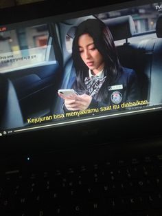 a woman is looking at her cell phone while sitting in the backseat of a car