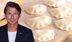 a man is standing in front of some dumplings on a cutting board with a rolling pin