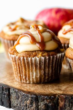 three cupcakes with caramel and white frosting sitting on a wooden board