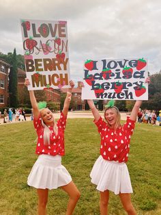 two girls holding up signs in the grass