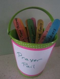 a green bucket filled with lots of different colored plastic spoons and writing on them