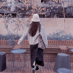 a woman walking down a brick walkway next to tables