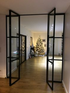 an open door leading to a living room with a christmas tree in the corner and lights on