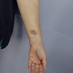 a small elephant tattoo on the left wrist is shown in front of a woman's arm