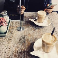 two people sitting at a table with coffee and photos