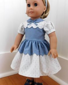 the doll is wearing a blue dress with white polka dots and a bow on her head