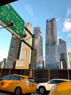 two taxi cabs are stopped at an intersection with skyscrapers in the background