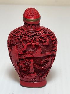 a red vase sitting on top of a white table