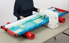 a woman is using a sewing machine to sew fabric on a long piece of cloth