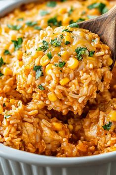 a wooden spoon scooping out some rice and corn into a casserole dish