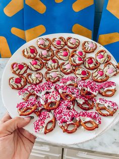 a white plate topped with lots of pretzels covered in pink sprinkles