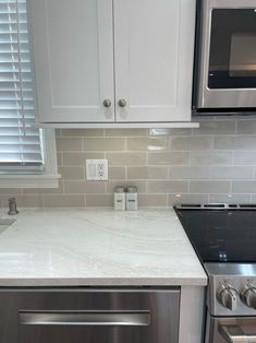 a kitchen with white marble counter tops and stainless steel appliances in front of the stove