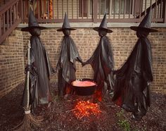 three plastic witches holding hands in front of a fire pit with red flame coming out of it