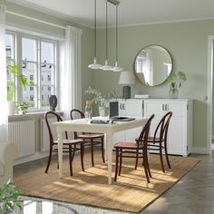 a dining room table with four chairs and a round mirror on the wall above it