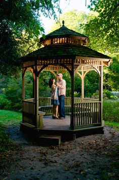 an older couple standing under a gazebo in the park