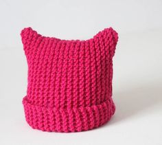 a pink knitted pillow sitting on top of a white table