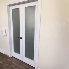 a white door with frosted glass in a room next to a wall and wood floor