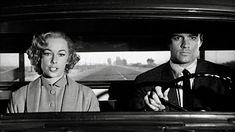 a man driving a car with a woman behind the wheel