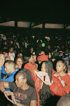 a group of people standing around each other at a concert with their hands in the air