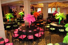 tables and chairs are set up with pink, green and yellow centerpieces in the shape of palm trees