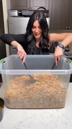 a woman holding a knife in a plastic container filled with food on top of a counter