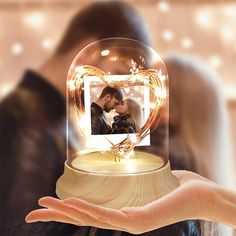 a person holding a snow globe with an image of a man and woman in it