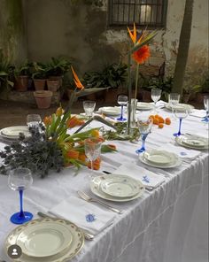 the table is set with plates, silverware and flowers in vases on it