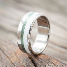 a wedding ring that is sitting on top of a piece of wood with green and white stripes