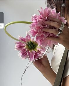 a woman holding a pink flower in her hand