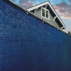 a house with a blue privacy fence in front of it and the sky behind it