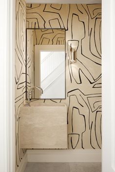 a bathroom with a sink, mirror and wallpaper on the walls in black and white