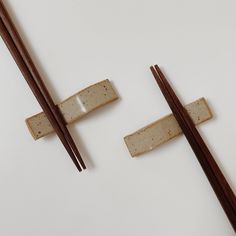 two chopsticks are sitting next to each other on a white surface, one with brown sticks sticking out of it