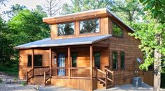 a small wooden cabin in the woods with stairs leading up to it's second floor