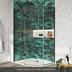 a bathroom with green tiles and white towels on the counter, shower stall and towel rack