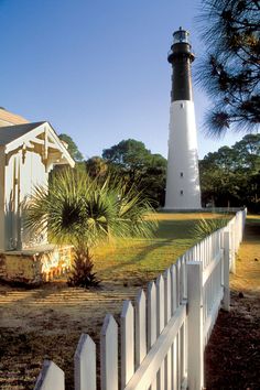 a white picket fence with a light house in the background