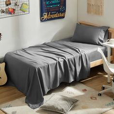 a bedroom with a bed, desk and guitar on the wall next to an area rug