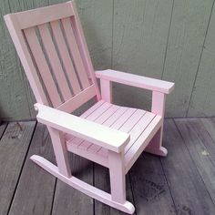 a pink rocking chair sitting on top of a wooden floor