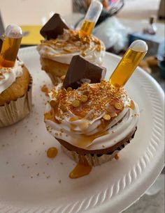 three cupcakes on a white plate topped with frosting and caramel topping