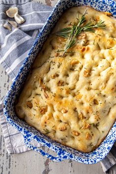 a casserole dish with cheese and herbs in it on a blue and white cloth