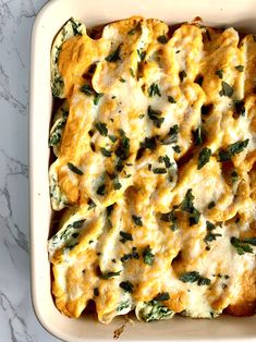 a casserole dish with cheese and spinach in it on a marble surface