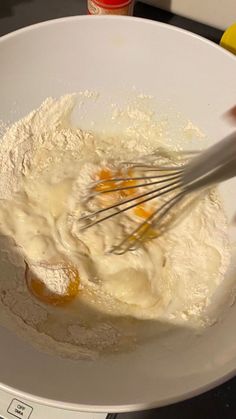 someone is whisking eggs in a white bowl