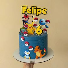 a hand holding up a cake with pokemon figurines on it and the words felpe above it