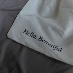 a white bag with the words hello beautiful on it sitting on top of a bed