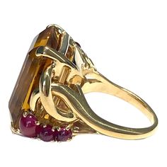 Crafted in 14K yellow gold, the ring features a large rectangular cut citrine solitaire accented by three round ruby cabochons on each side. Citrine: 25 ct. 6 Rubies: 1.60ctw. Measurements: Front: 21.5 mm H x 25 mm W x 12.5 mm D Weight: 26.2 grams Size: 8.5 (sizable) Marked: 14K Formal Multi-stone Rectangular Ring, Gold Multi-stone Rectangular Ring, Gold Rectangular Amethyst Ring For Formal Occasions, Luxury Gold Three-stone Ruby Ring, Luxury Gold Ruby Three Stone Ring, Gold Rectangular Ruby Ring, Luxury Gold Three Stone Ruby Ring, Luxury Gold Rectangular Topaz Ring, Luxury Gold Ruby Ring With Three Stones