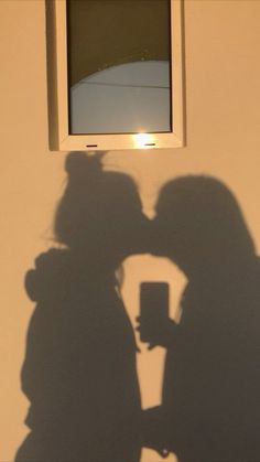 two people standing next to each other in front of a window with the sun shining through