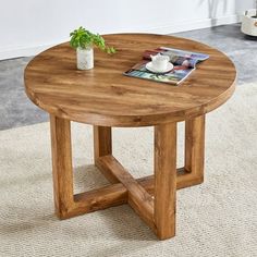 a small wooden table with a magazine on it's side and a potted plant in the middle